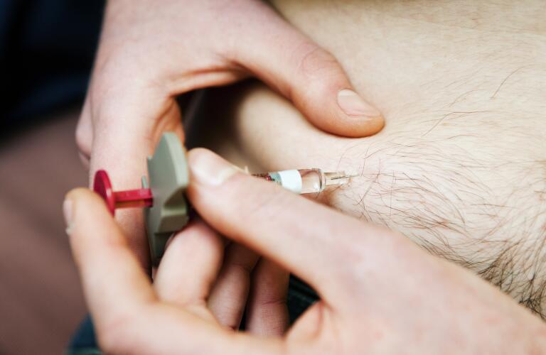 closeup of man giving himself an injection of biologic drug into his stomach