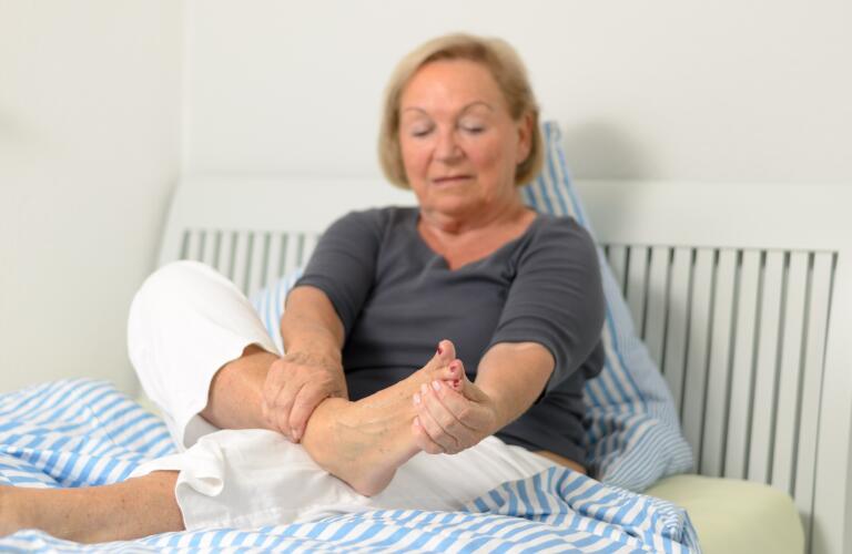 senior woman on bed holding foot
