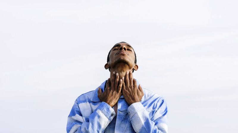 man with neck extended upwards and hands across it vertically