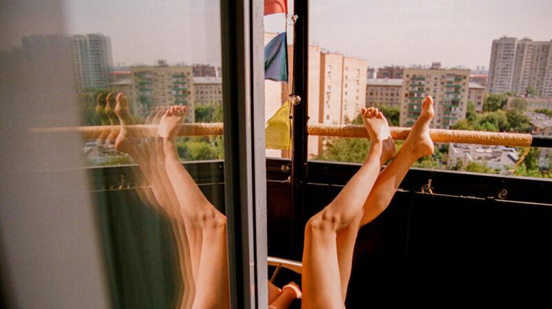 Unseen woman's legs leaning against balcony from floor