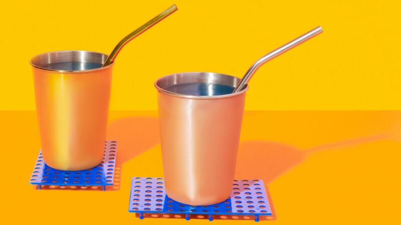 there are two yellow metal cups on blue coasters