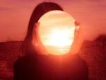 Woman Holding Mirror Against Face While Standing Outdoors During Sunset