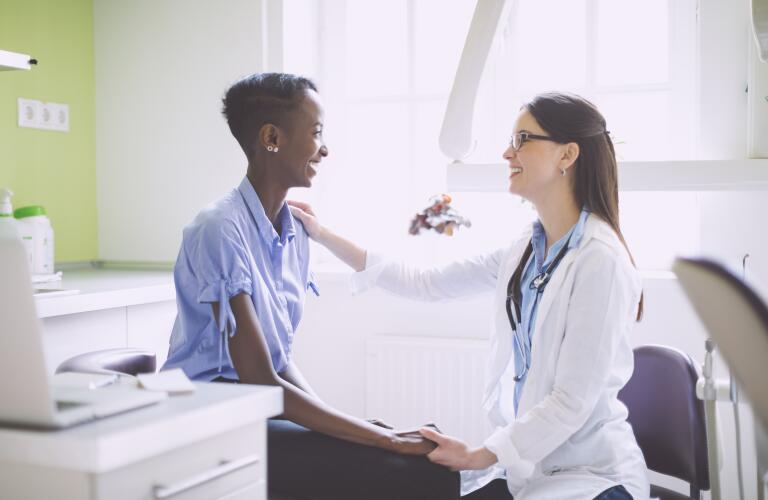 Young African American female patient talking to young Caucasian female doctor