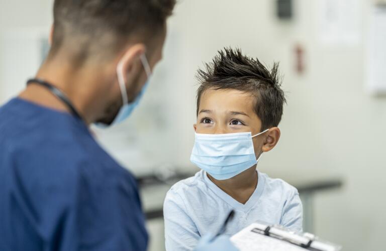 young boy and doctor wearing disposable surgical masks at doctor's appointment