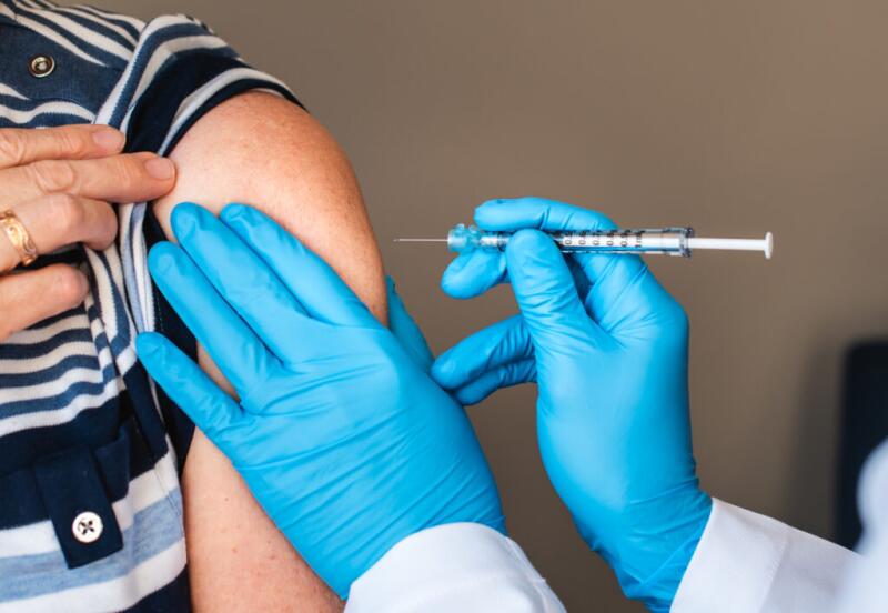 Close up of woman getting injected with a vaccine in upper arm.