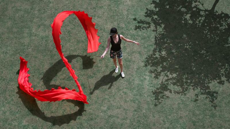 woman outside twirling large, bright red ribbon