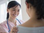 smiling female doctor with hand on patient's shoulder