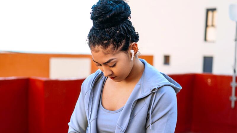 A person looks down while wearing in-ear earphones.