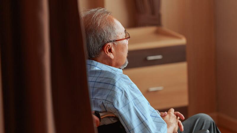 Rear viewer of older adult male sitting in office or waiting room
