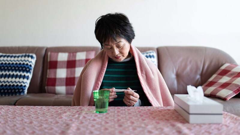 A woman checking her temperature with a thermometer