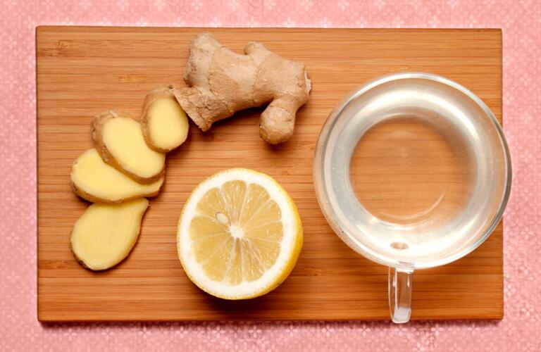 ginger root and lemon next to cup of hot water