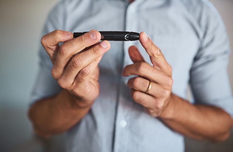 portrait of man holding insulin pen to finger