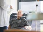 senior Caucasian male receiving chemotherapy in hospital speaking with doctor