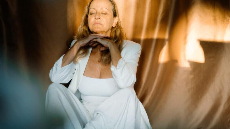 A woman sitting and meditating with her eyes closed