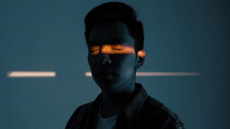 Person in shadows with a light across their closed eyes