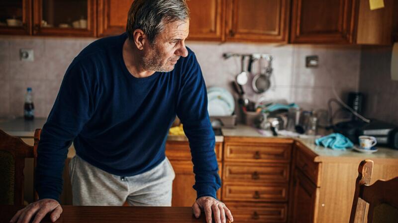 Man steading himself by leaning on a table