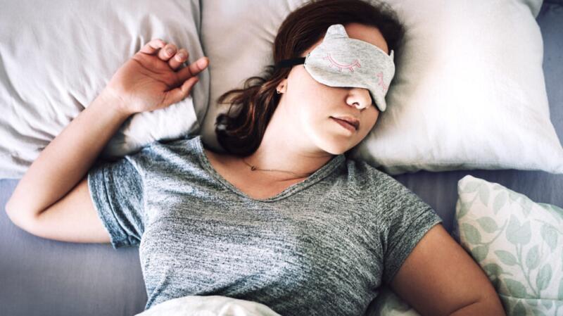 Woman asleep in bed with face mask on lying on back