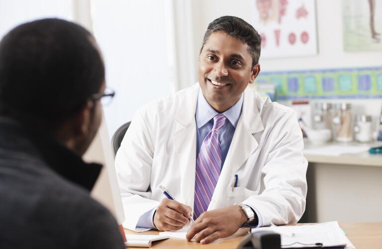 male doctor smiling and talking with male patient in office