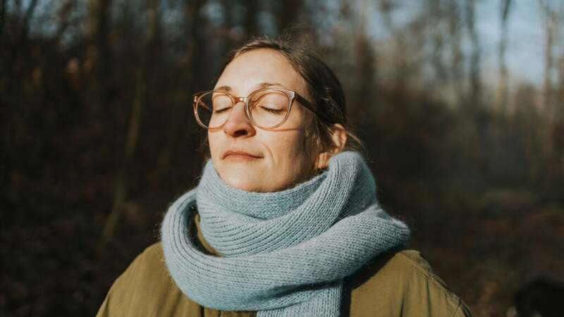 A person standing in the sun with a thick scarf around their neck