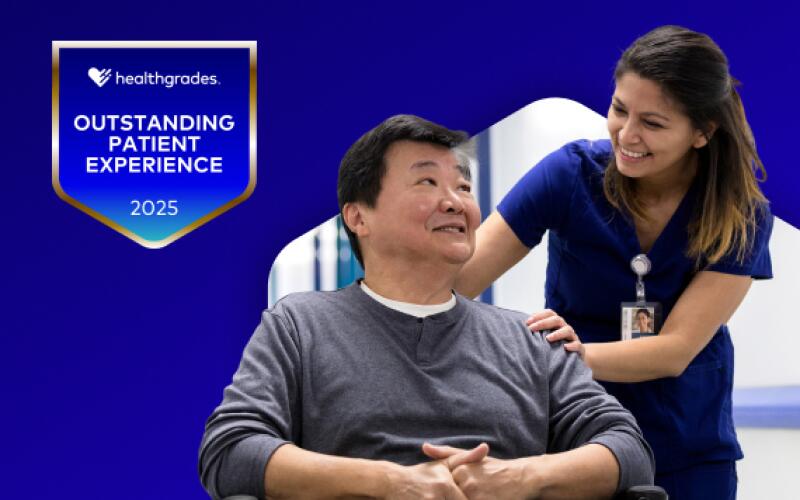 Stock image featuring a young female doctor wearing blue scrubs pushing a male patient in a wheelchair down a hospital corridor. To the left of the stock image, a 2025 Healthgrades Outstanding Patient Experience Award is superimposed against a blue gradient background.