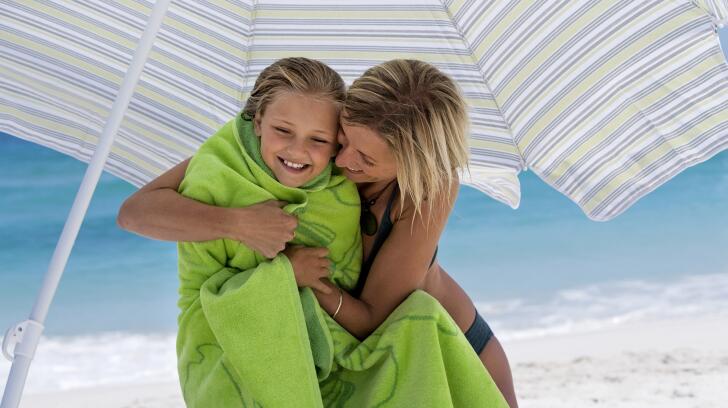mother embracing daughter under sunshade