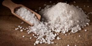 mound of sea salt on table with wooden spoon