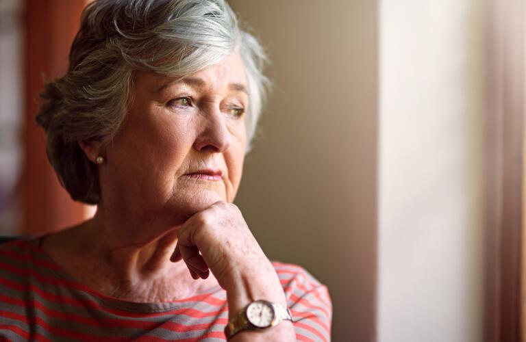Senior Caucasian woman looking out window in deep thought or concern