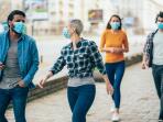 young people wearing face masks walking together along a city street