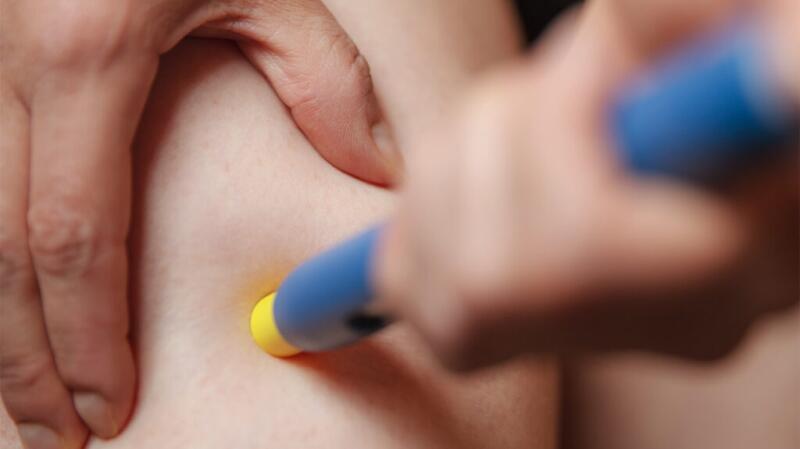 This is a close up of a person using an EpiPen.