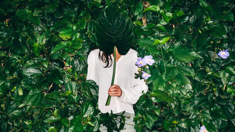 person covering face with leaves