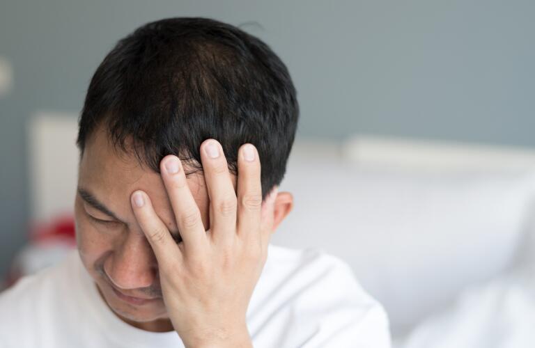 Asian American man holding front of head in pain