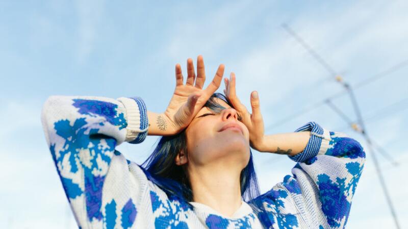 a woman is outside with her hands on her forehead