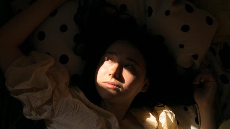 woman lying flat in bed with look of concern