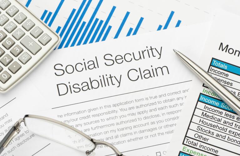 social security disability claim with calculator glass and pen