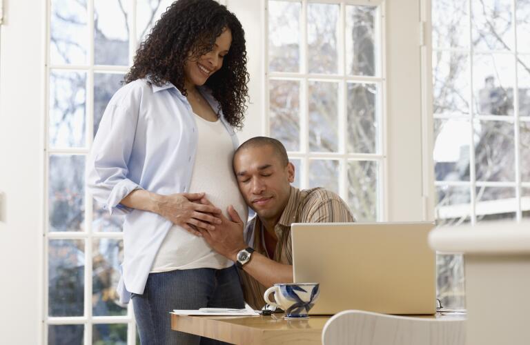 Young African American father listening to pregnant wife's belly