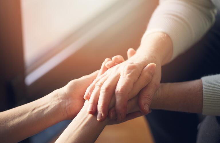 closeup of two pairs of hands holding in soft light