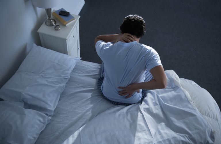 man-with-back-pain-sitting-up-in-bed