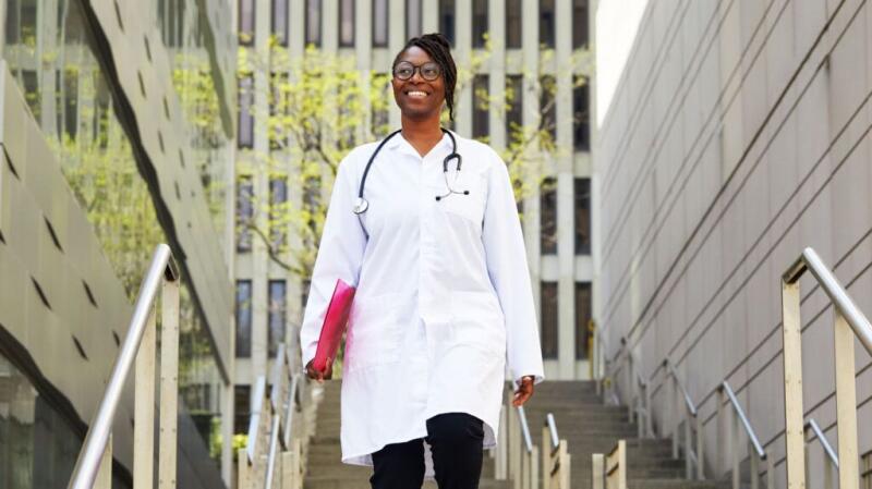 Smiling female doctor walking down the stairs outside.
