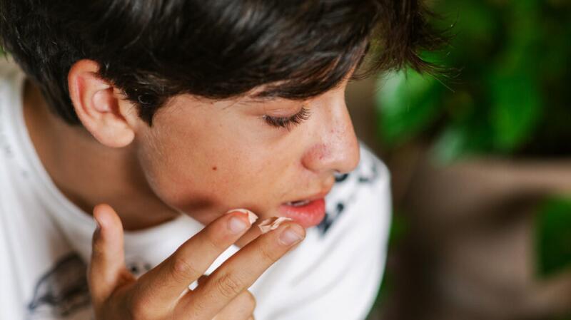 A person is applying cream to their jawline.