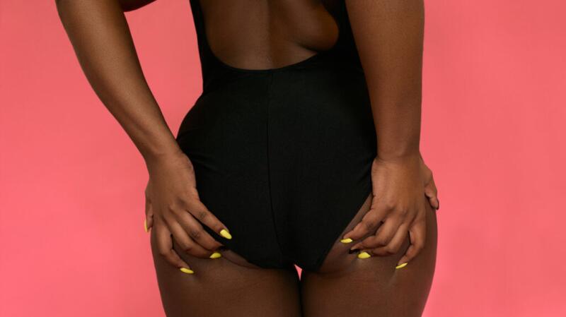 Image of the back of a female standing with her hands on her buttocks
