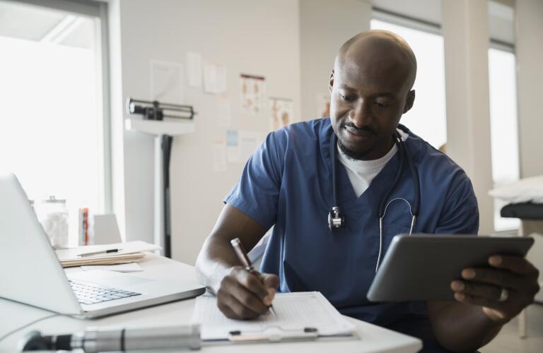 Doctor in scrubs with digital tablet and clipboard