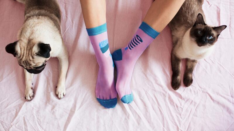 Overhead photo of unseen person's feet on bed wearing pink and blue socks