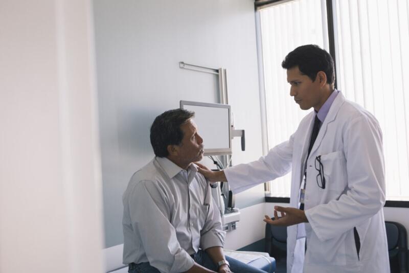 Male doctor discussing illness with senior patient