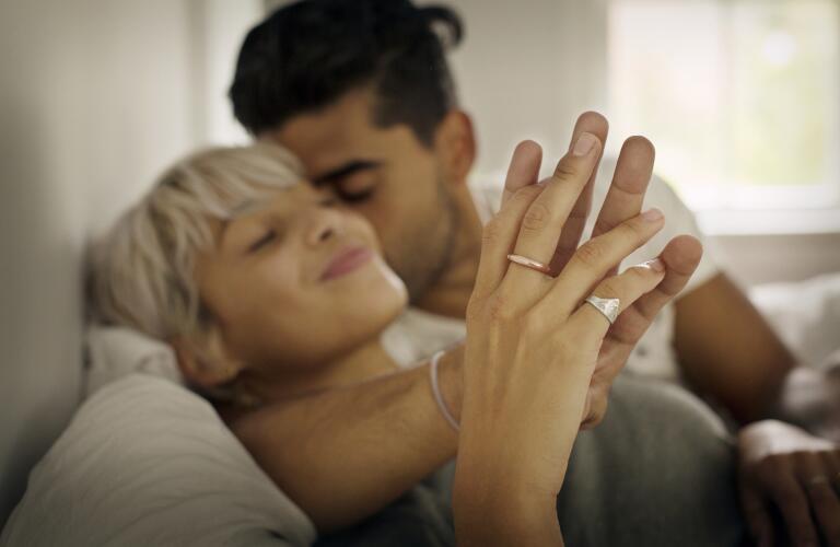 Couple snuggling and holding hands in bed