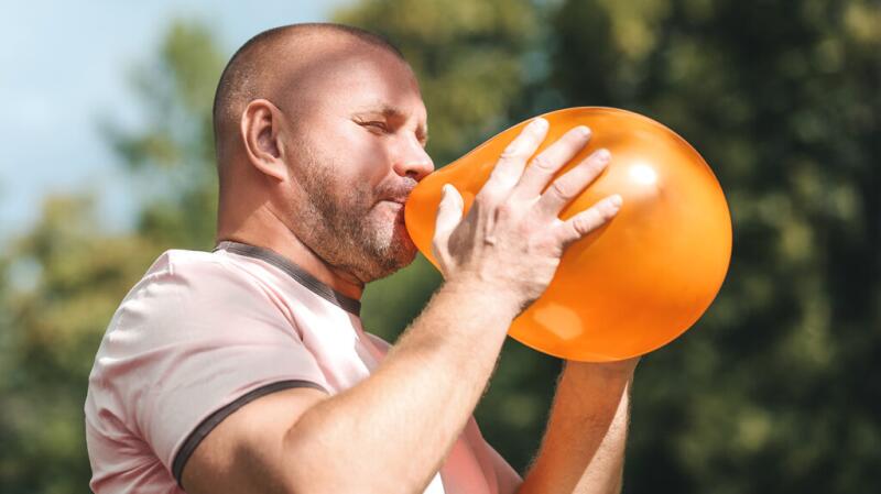 Male blowing up a balloon