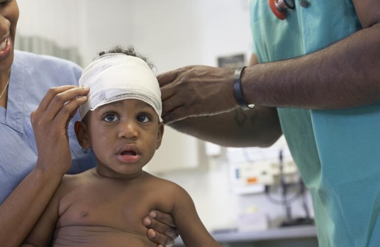 Young African American toddler getting head bandage at doctor's office
