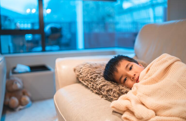 Young child resting under blanket on couch
