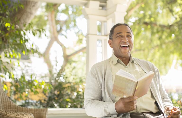 laughing-senior-man-reading-on-porch