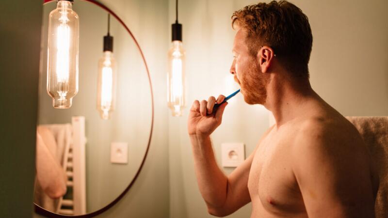 Person brushing their teeth in front of a mirror