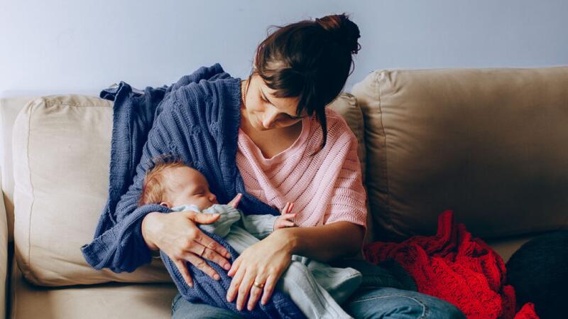 Mother holding baby on sofa